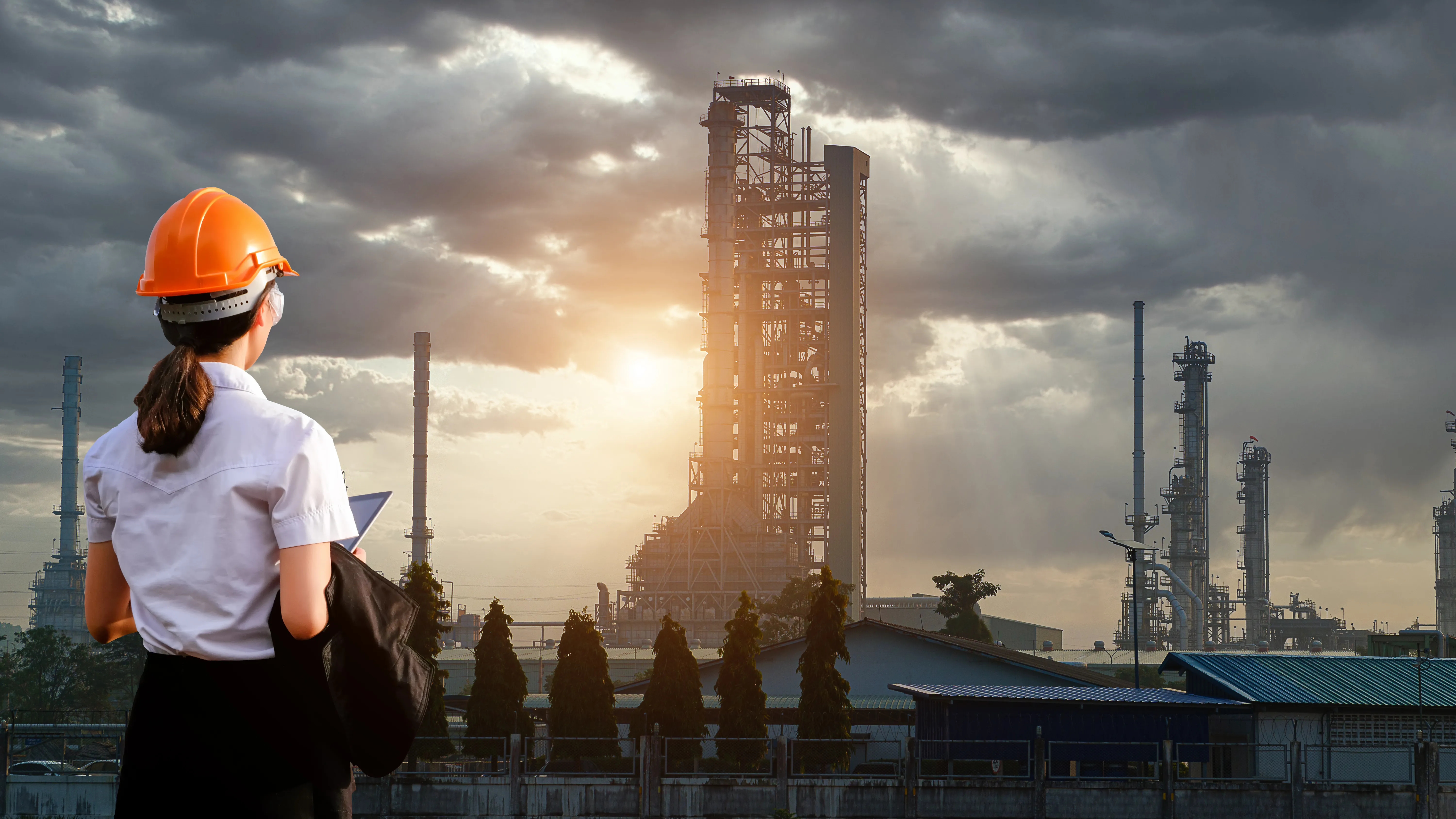 Engineer surveying a refinery at sunset