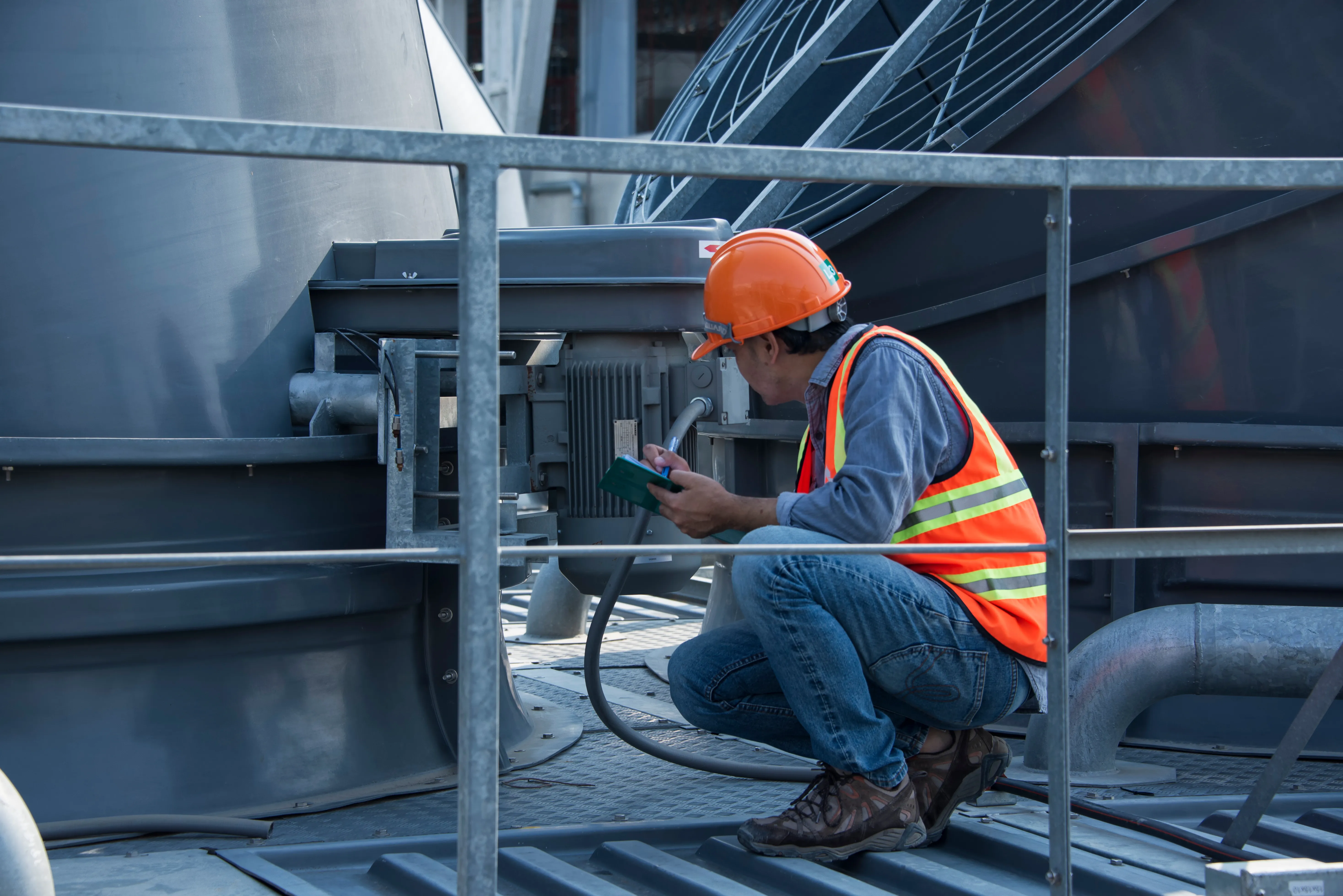 Engineer logging readings on rooftop cooling-tower plant